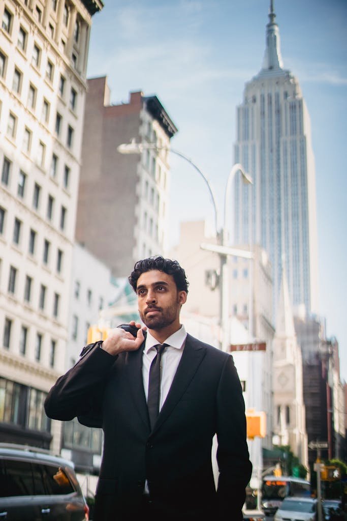 A well-dressed businessman walking confidently with the Empire State Building in the background.