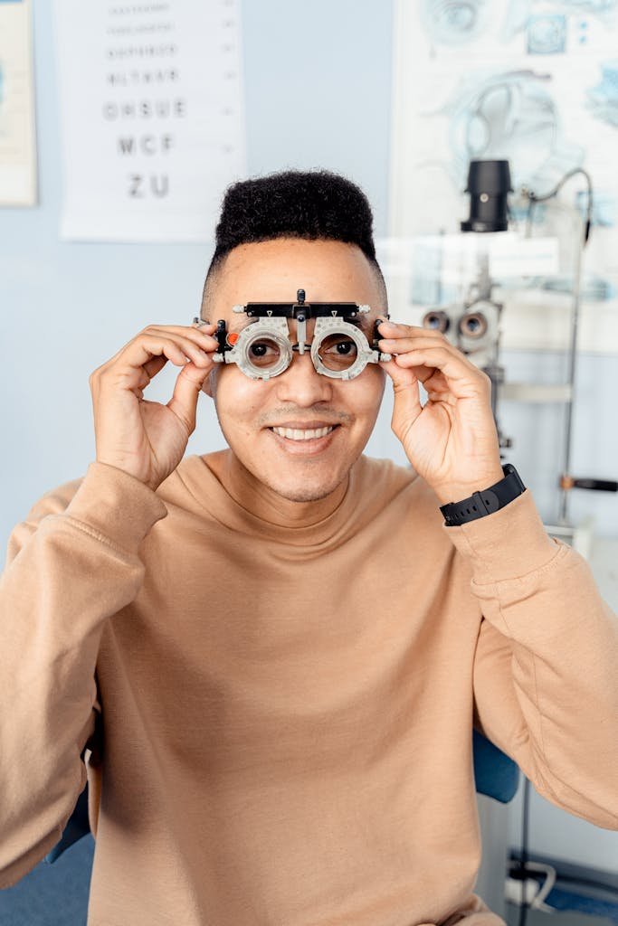 Man smiling while holding trial frames during an eye exam at an optometrist's office.