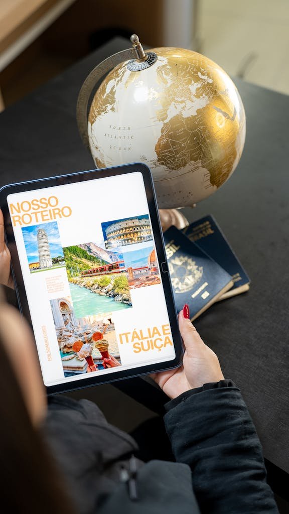 Traveler planning a trip to Italy and Switzerland using a globe, tablet, and passports.